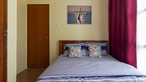 A bedroom with a bed, a door, a painting, and a window with curtains. - Condo near diving spots +fast wifi+netflix (Lapu-Lapu City)