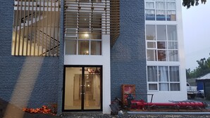 A modern building with a large glass door entrance, a staircase with wooden railings, and a red fire hose on the ground. - Condo near diving spots +fast wifi+netflix (Lapu-Lapu City)