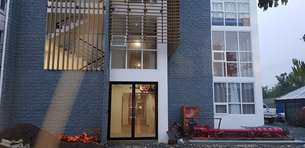 A modern building with a large glass door entrance, a staircase with wooden railings, and a red fire hose on the ground.