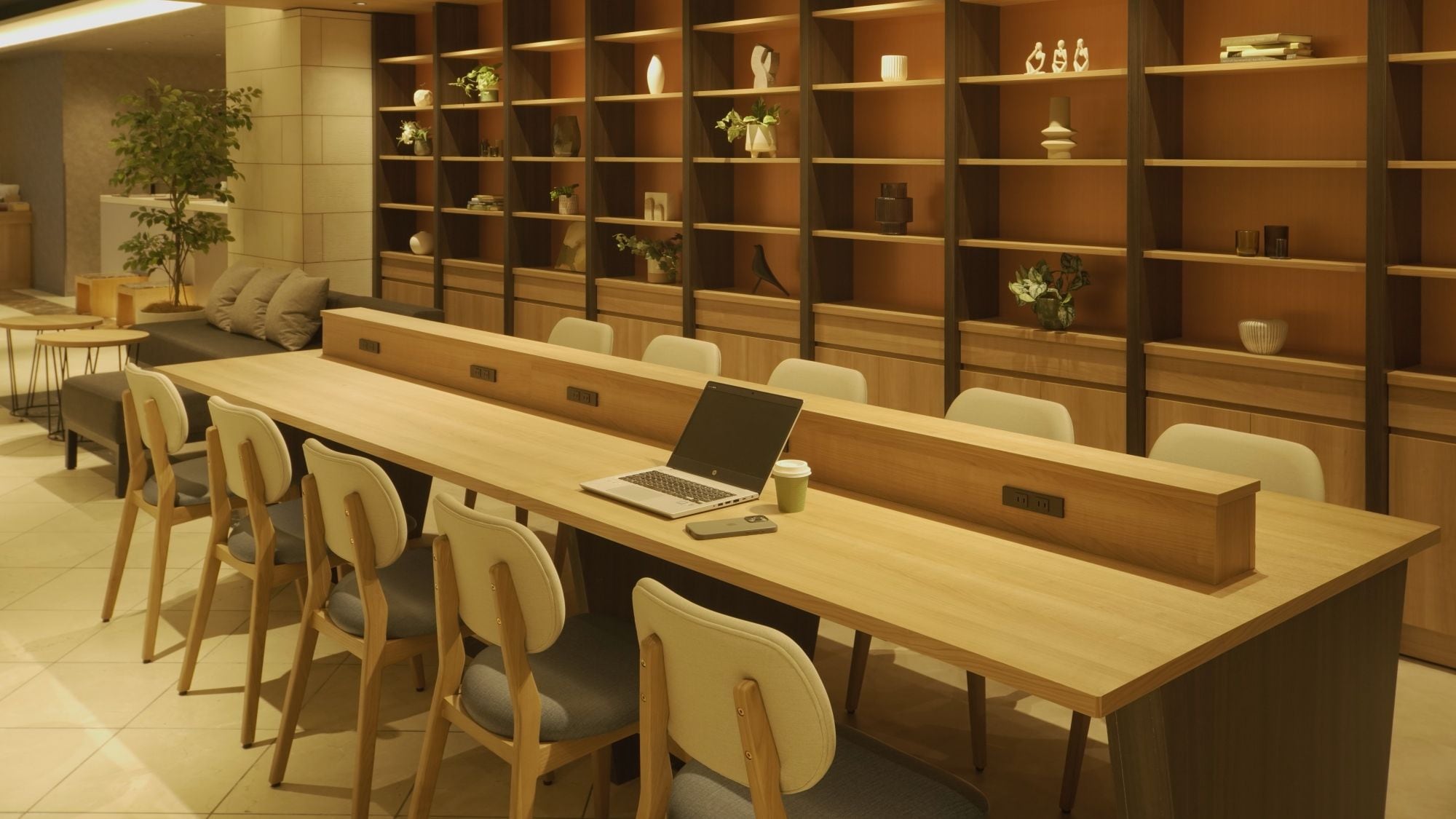 A modern meeting room with a long table, chairs, and a laptop.
