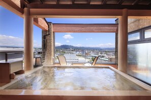 Un jacuzzi con vistas a un paisaje urbano y montañas.