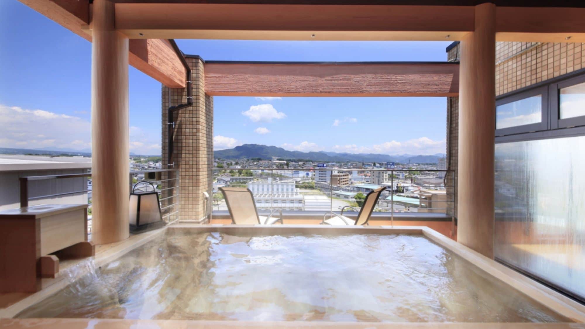 A hot tub with a city view, a brick wall, and a glass railing.