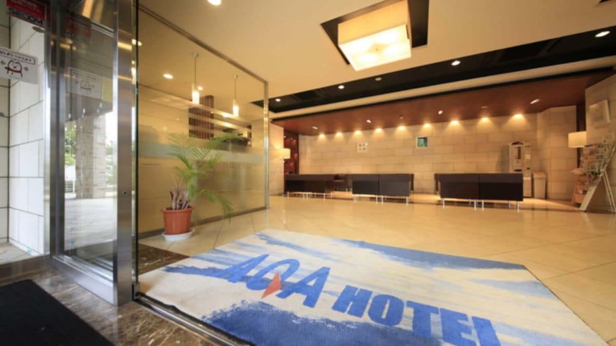 A hotel lobby with a reception desk, a waiting area, and a glass entrance.