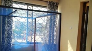Una habitación con cama, ventilador de techo y ventana con vistas al exterior.
