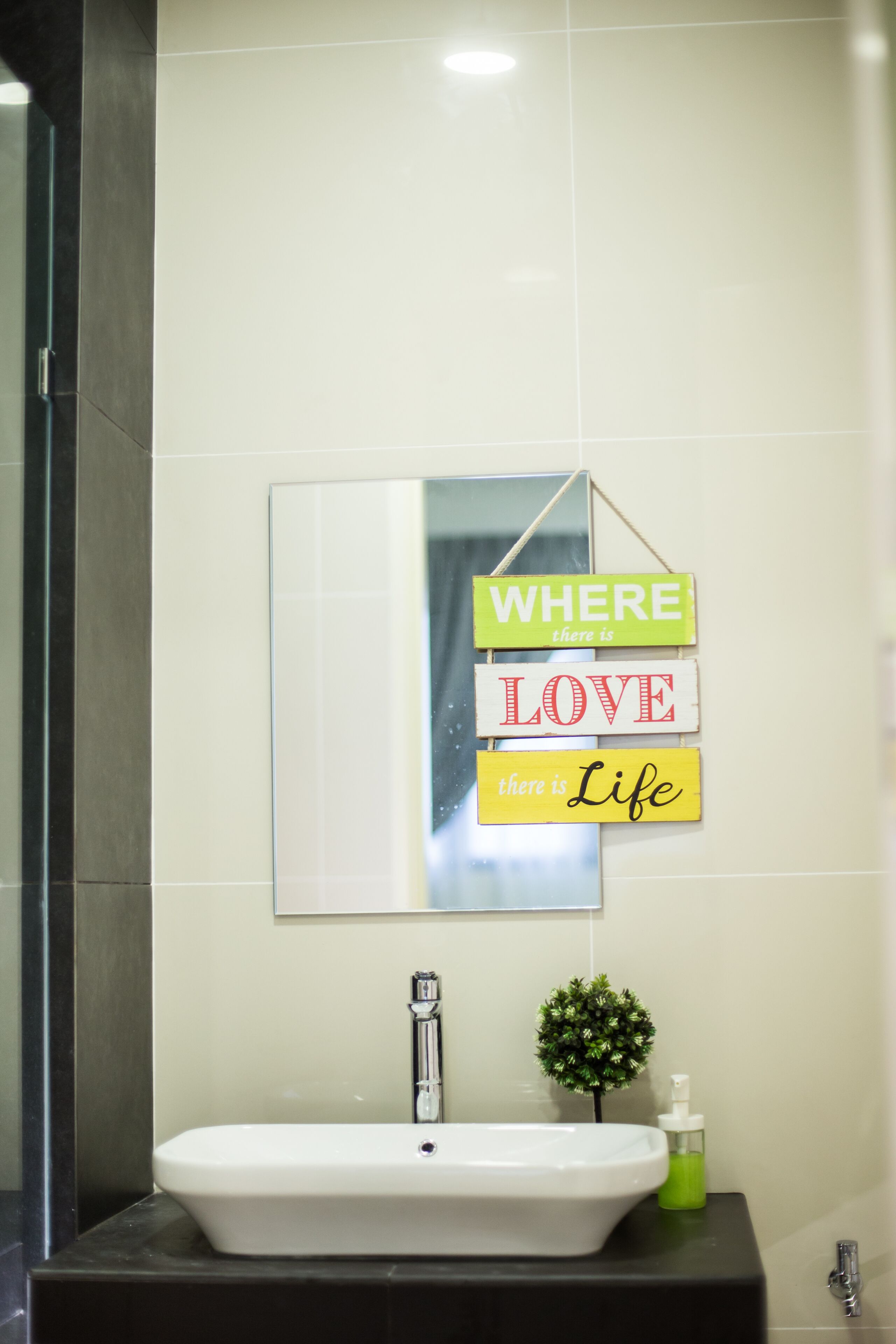 A bathroom with a white sink, a mirror, and a motivational sign saying "WHERE there is LOVE there is Life".