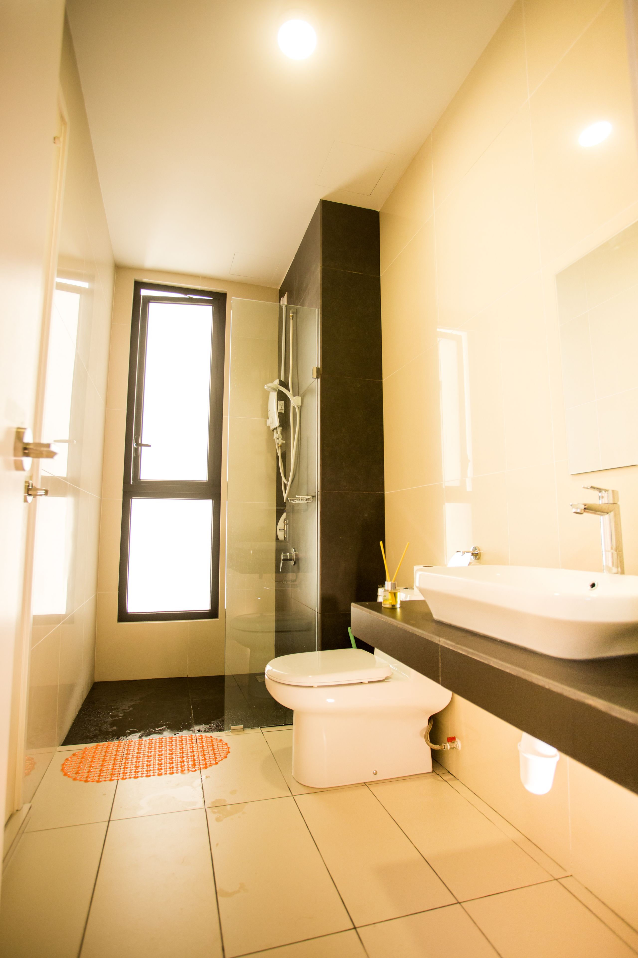 Un baño moderno con cabina de ducha de vidrio, un inodoro blanco y un espejo grande sobre el lavamanos.