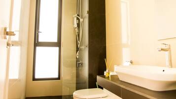 Un baño moderno con cabina de ducha de vidrio, un inodoro blanco y un espejo grande sobre el lavamanos.