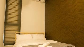 A bedroom with a bed, a ceiling fan, an air conditioning unit, and a window with blinds.