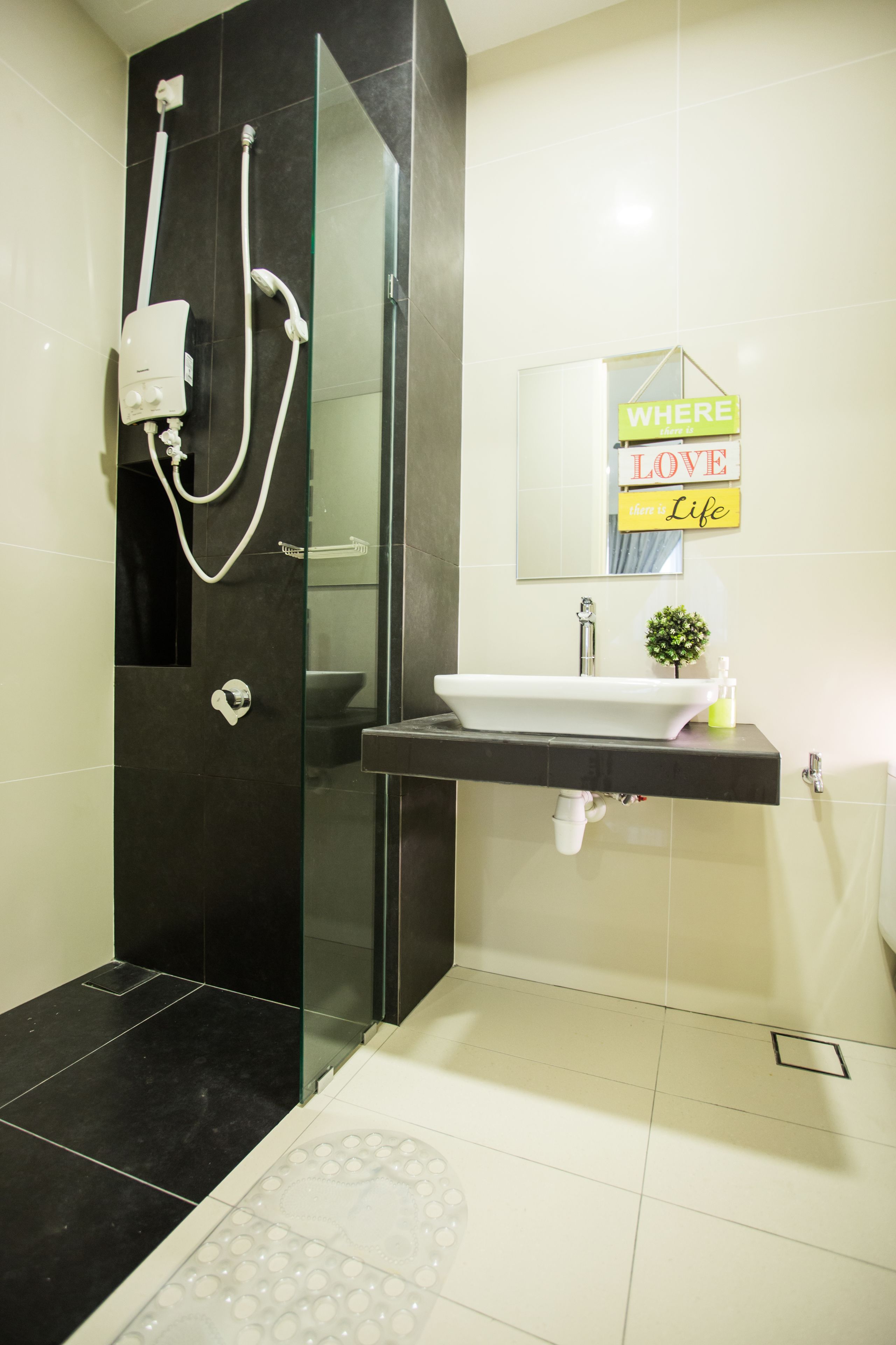 A modern bathroom with a glass-enclosed shower, a sink with a mirror, and a sign that reads "WHERE LOVE THEN LIFE".