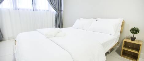 A neatly made bed with white linens in a bright room with a window and a small wooden nightstand with a plant.