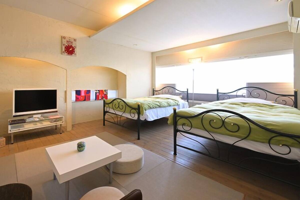 A hotel room with two beds, a TV, a small table, and a couch.