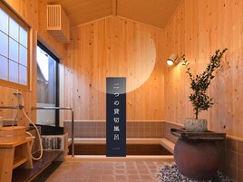 Un interior de madera con una sauna, una planta en maceta y un letrero con caracteres japoneses.