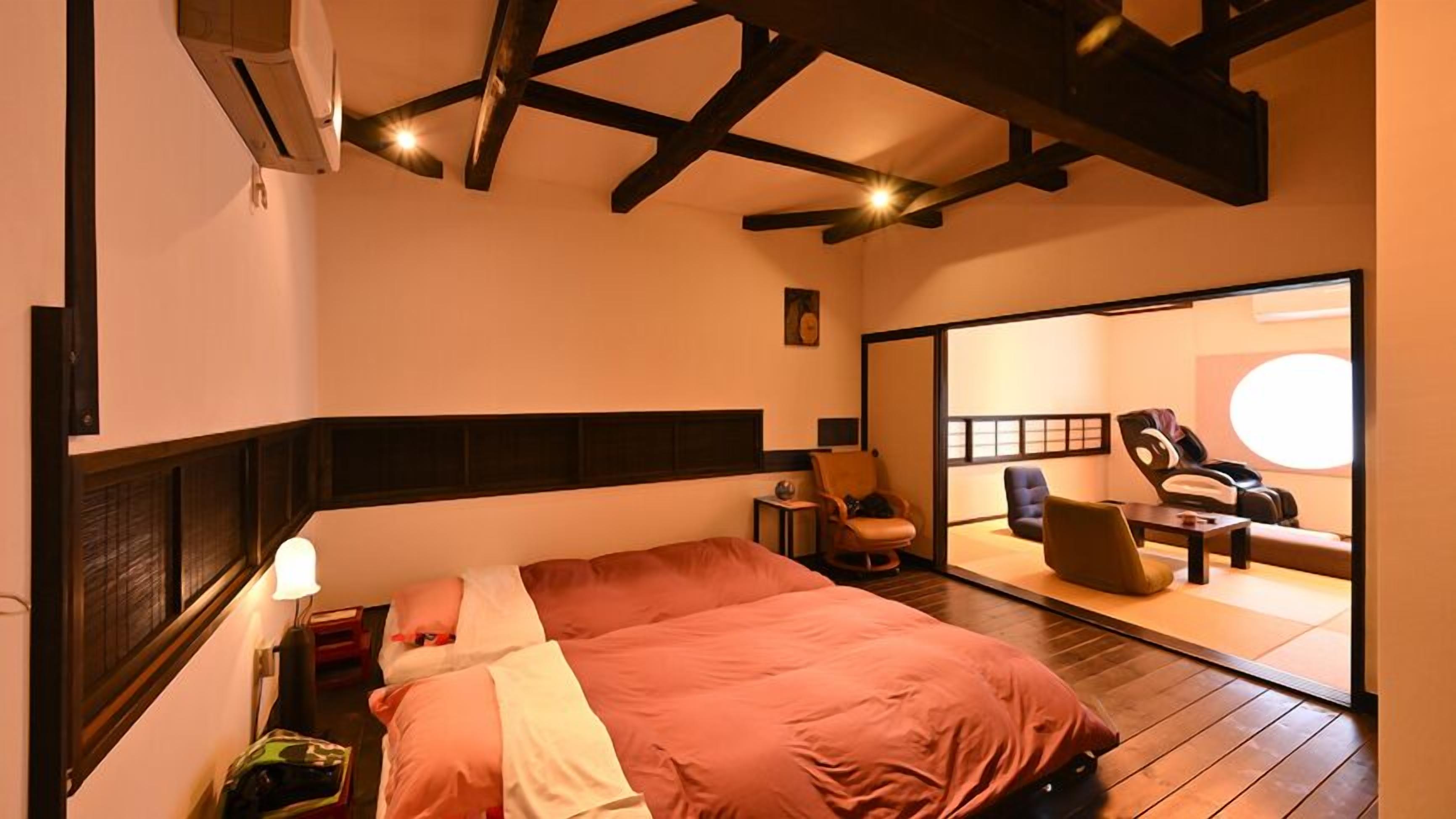Ein Hotelzimmer mit einem großen Bett, einer Sitzecke mit Sesseln, einem Massagesessel und einem großen Spiegel.