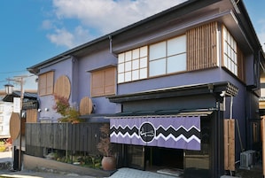 Un edificio japonés tradicional con fachada morada, amplias ventanas y una valla de madera.