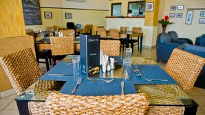 Un restaurante con sillas de mimbre, manteles azules y un atril para el menú.