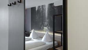 A modern bedroom with a bed, white pillows, and a wall-mounted shelf. - Hotel Schwarzwälder Hof (Freiburg im Breisgau)