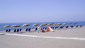 A beach with rows of blue lounge chairs and yellow umbrellas. - Homeholiday Giulivo (Cellole)