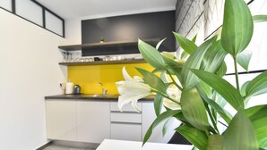 A modern kitchen with white cabinets, a yellow countertop, and a black backsplash. - Mono Apartments & Rooms (Zadar)