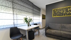 A modern room with a white table, two black chairs, a grey sofa, a patterned wall, and a framed artwork. - Mono Apartments & Rooms (Zadar)