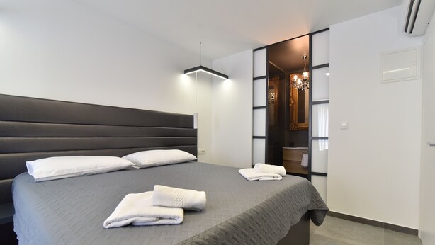 A modern hotel room with a large bed, a bedside table, and a wardrobe. - Mono Apartments & Rooms (Zadar)