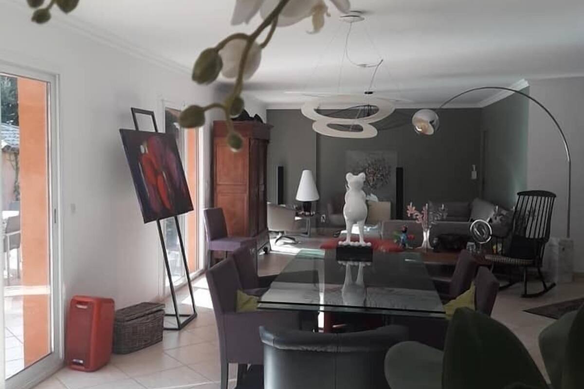 Una sala de estar moderna con una mesa de comedor de vidrio, asientos cómodos, un ventanal y vistas al exterior.
