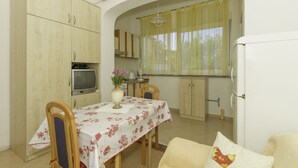 A compact kitchen with a dining area, a TV, and a refrigerator. - Apartments Joso (Zadar)