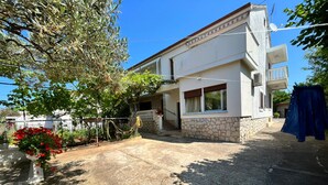 A two-story house with a stone foundation and a white exterior. - Apartments Joso (Zadar)