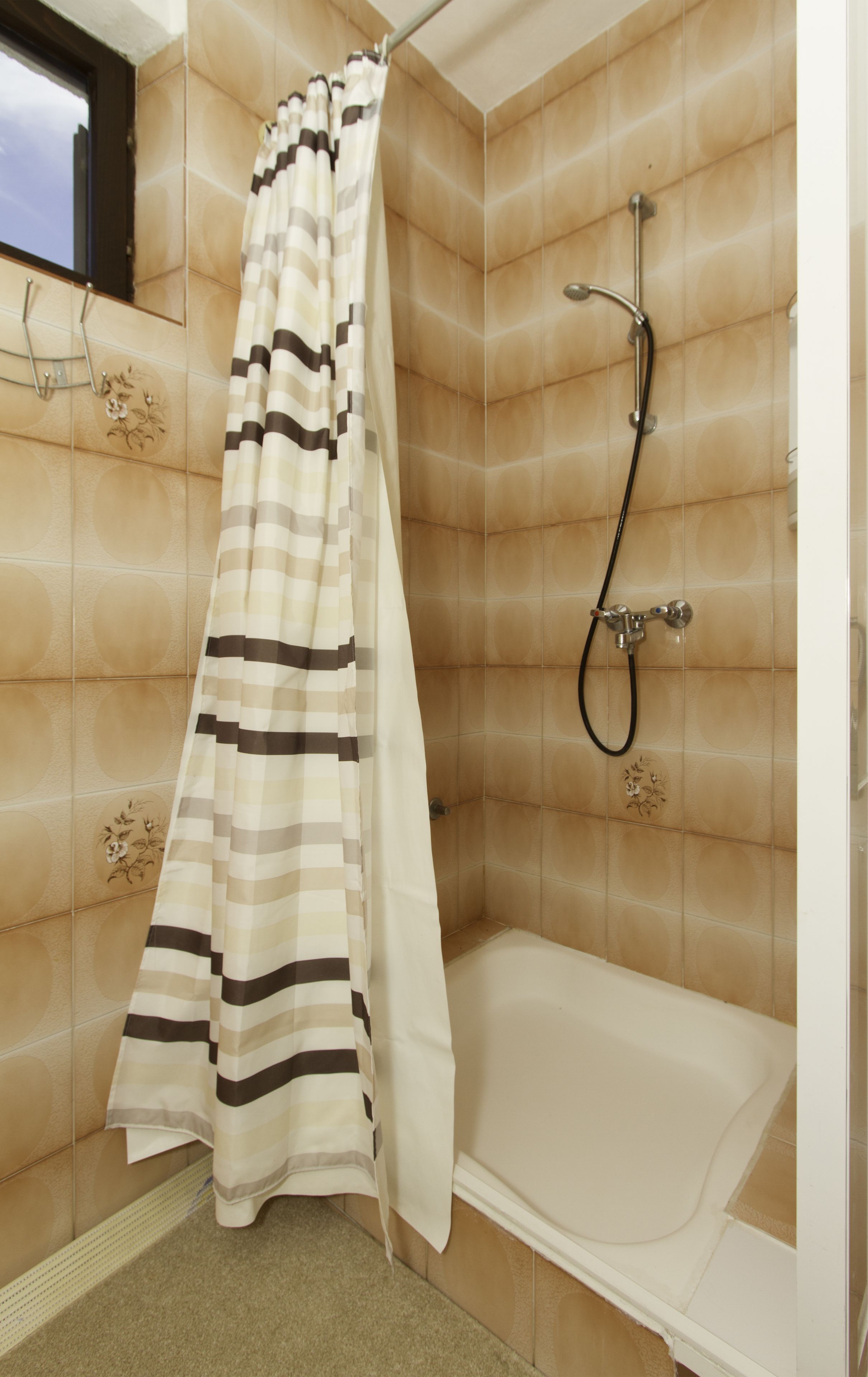 A bathroom with a shower curtain, a bathtub, and tiled walls.