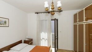 A bedroom with a bed, a nightstand, a wardrobe, and a chandelier. - Apartments Joso (Zadar)