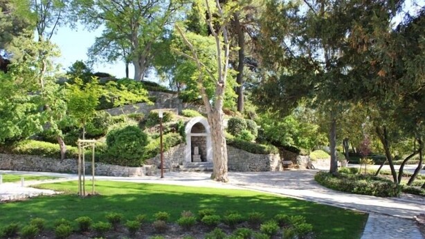 A landscaped garden with a stone pathway, neatly trimmed bushes, and a central arched entrance. - Apartments Joso (Zadar)