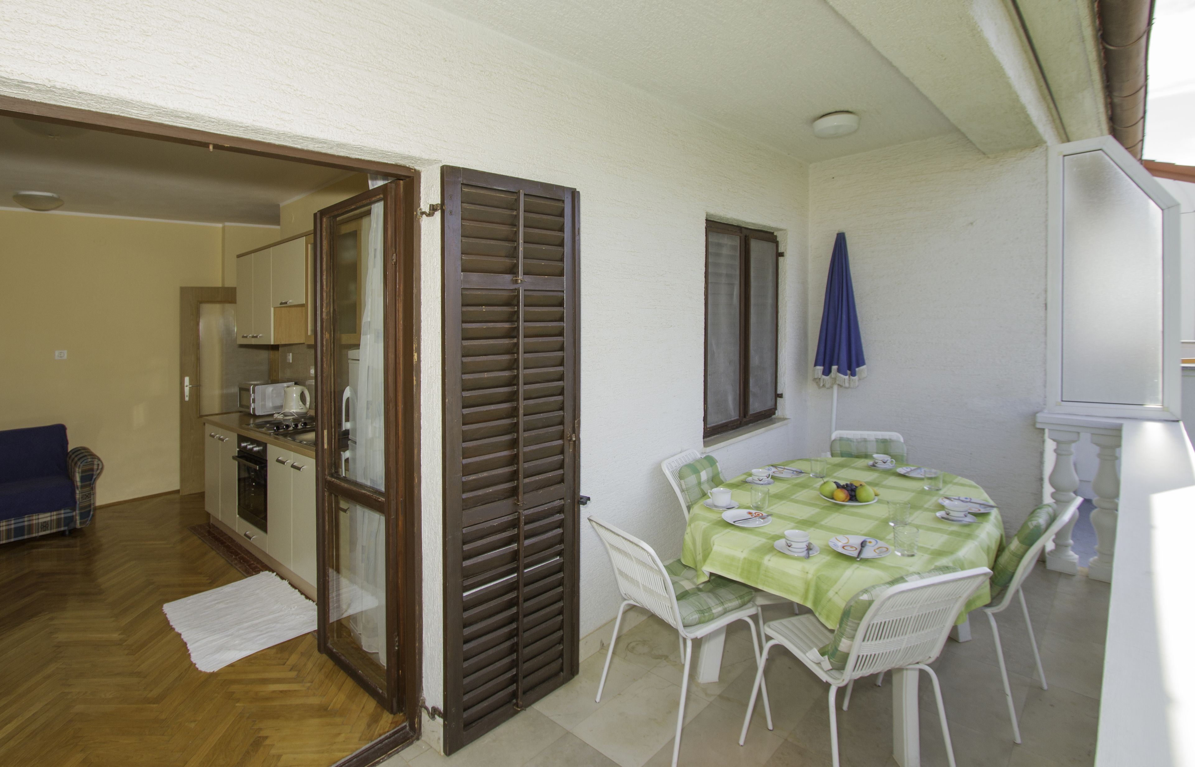 A compact kitchen with modern appliances, a dining area with a table set for two, and a blue umbrella near a window.