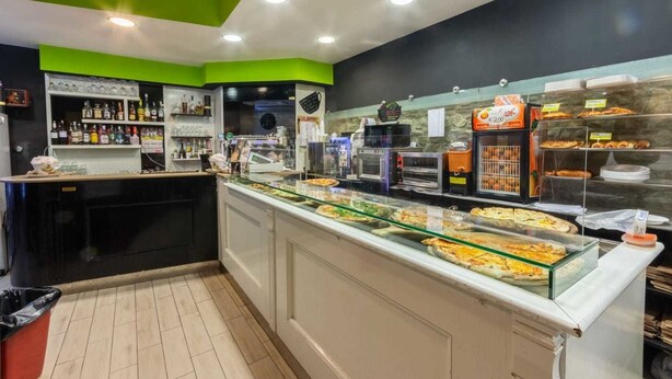 A buffet area with various food items displayed in glass cases, a coffee station, and shelves stocked with beverages. - B&B Il Castellino (Santo Stefano di Camastra)