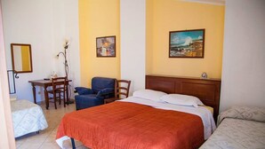 A hotel room with a large bed, two smaller beds, a desk, and chairs. - B&B Il Castellino (Santo Stefano di Camastra)