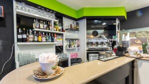 A bar area with shelves of liquor bottles, a coffee machine, and a bowl of napkins on the counter. - B&B Il Castellino (Santo Stefano di Camastra)