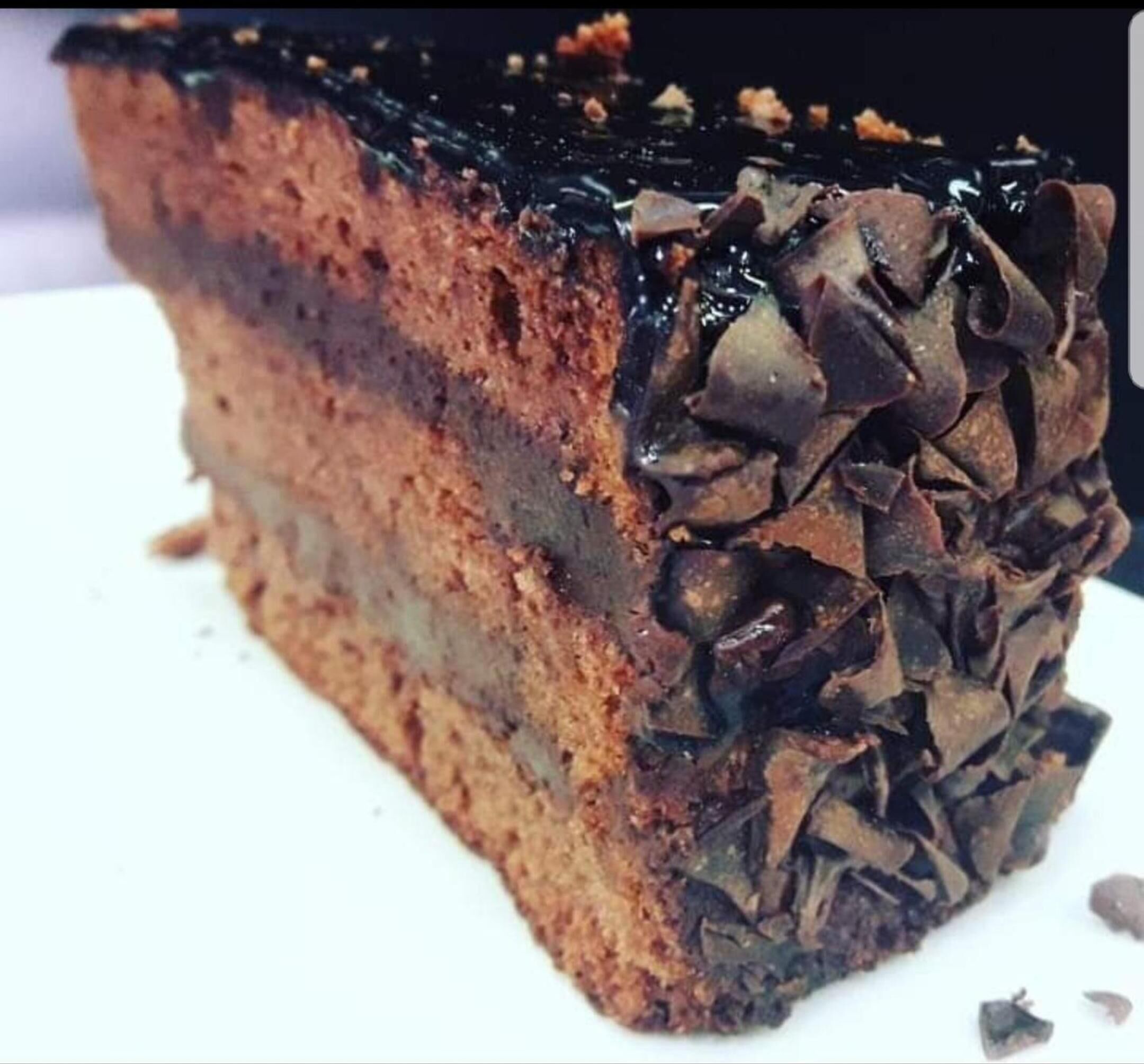 Een plak gelaagde cake met een glanzende chocoladelaag.
