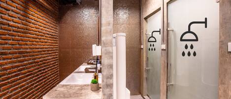 A modern bathroom with a brick wall, a large bathtub, and a glass shower enclosure.