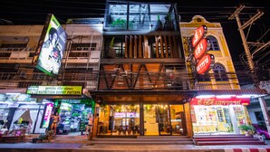 A multi-story building with a modern facade, a visible ground-floor shop, and a brightly lit upper level. - Kaen Hostel (Pattaya)