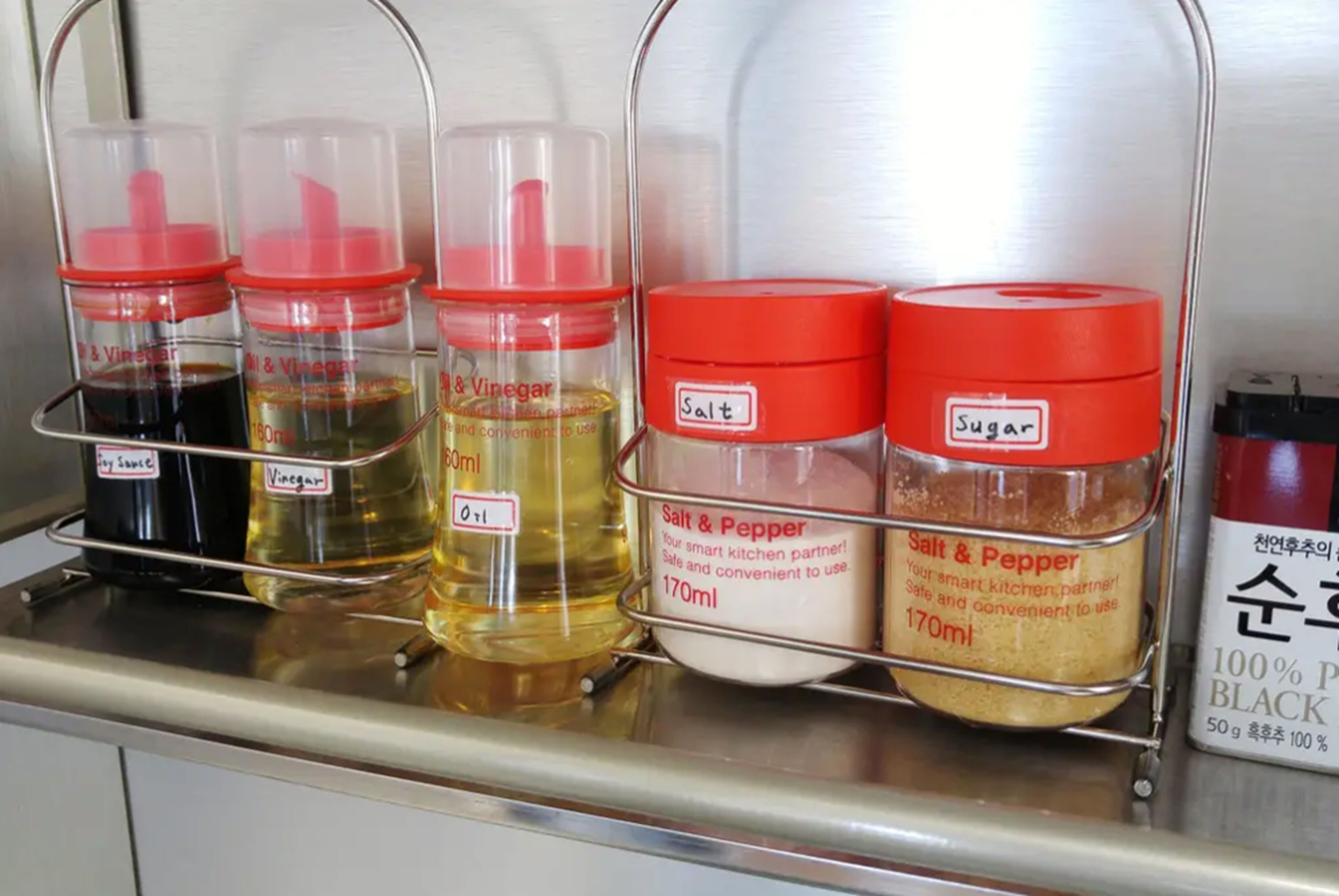 A kitchen shelf with condiment dispensers for soy sauce, vinegar, salt, and sugar.