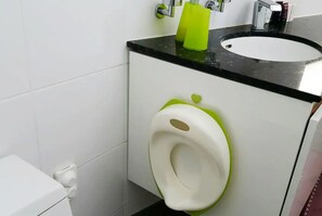 A bathroom with a white toilet, a green and white bidet, and a black countertop with a sink. - Equinoxe de Geumneung (Jeju City)