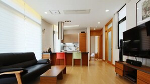 A modern living room with a black sofa, wooden coffee table, and a TV stand. - Equinoxe de Geumneung (Jeju City)