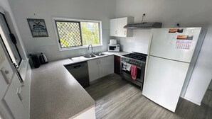 A kitchen with a dishwasher, stove, oven, microwave, and a refrigerator. - Ohana Hawaiian term meaning "family" (Agnes Water)
