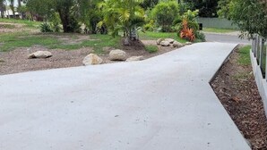 A concrete pathway with a white fence on one side and a landscaped garden with rocks and trees. - Ohana Hawaiian term meaning "family" (Agnes Water)