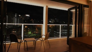 A balcony with two chairs and a table, overlooking a cityscape at night. - HOTEL Viviana (Naha)