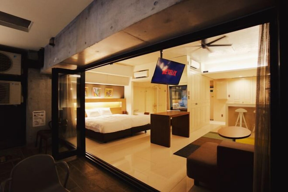 Una habitación de hotel moderna con una cama, un escritorio y una pantalla de televisión que muestra el logotipo de Netflix.