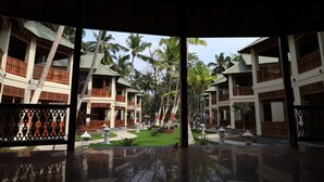 A resort with multiple buildings, each featuring balconies and a central courtyard with palm trees and a small pool. - Sandyy Wavess Beach Resort (Port Blair)