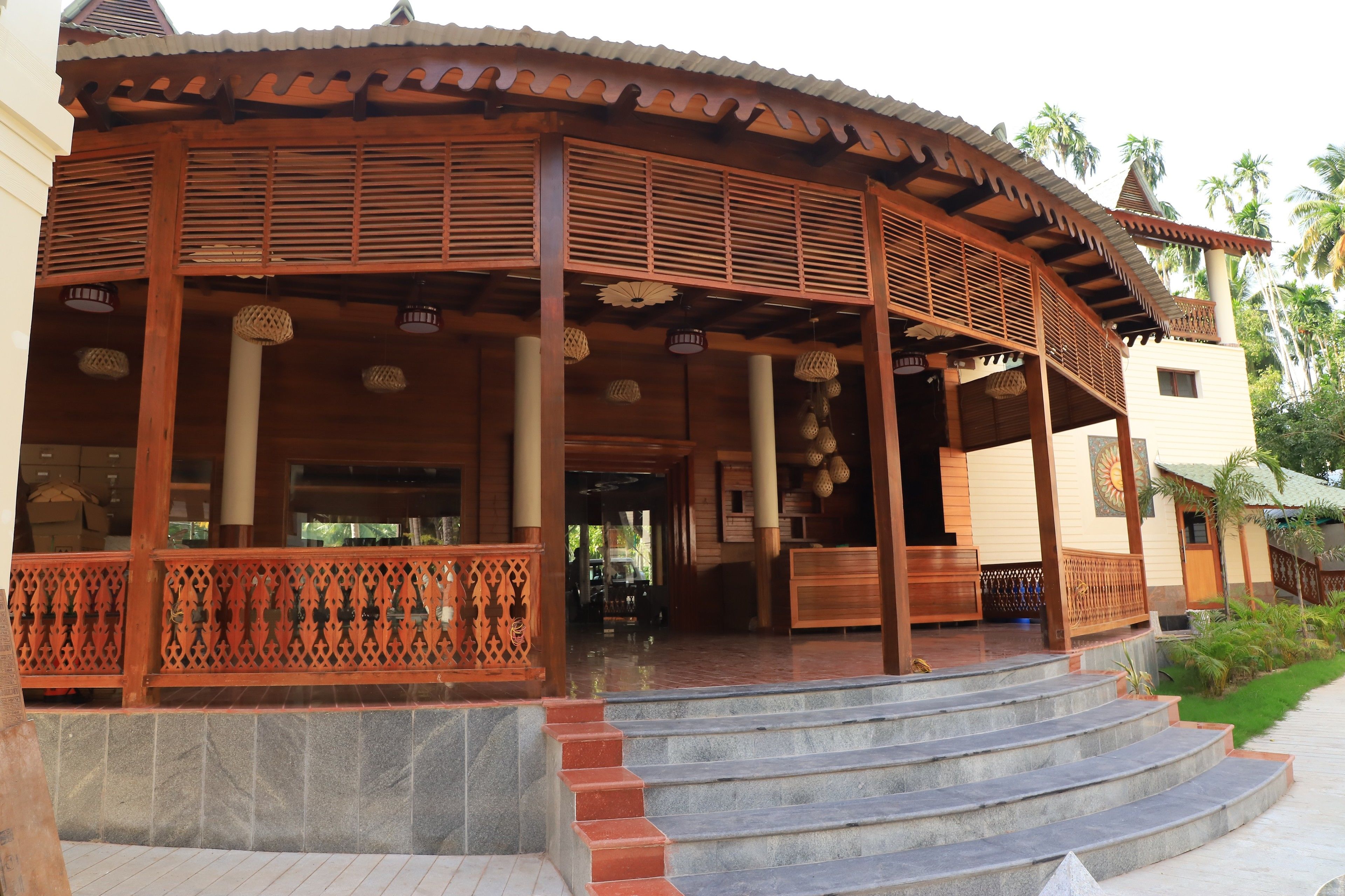 A traditional wooden building with a curved roof, a staircase leading to the entrance, and a decorative railing.