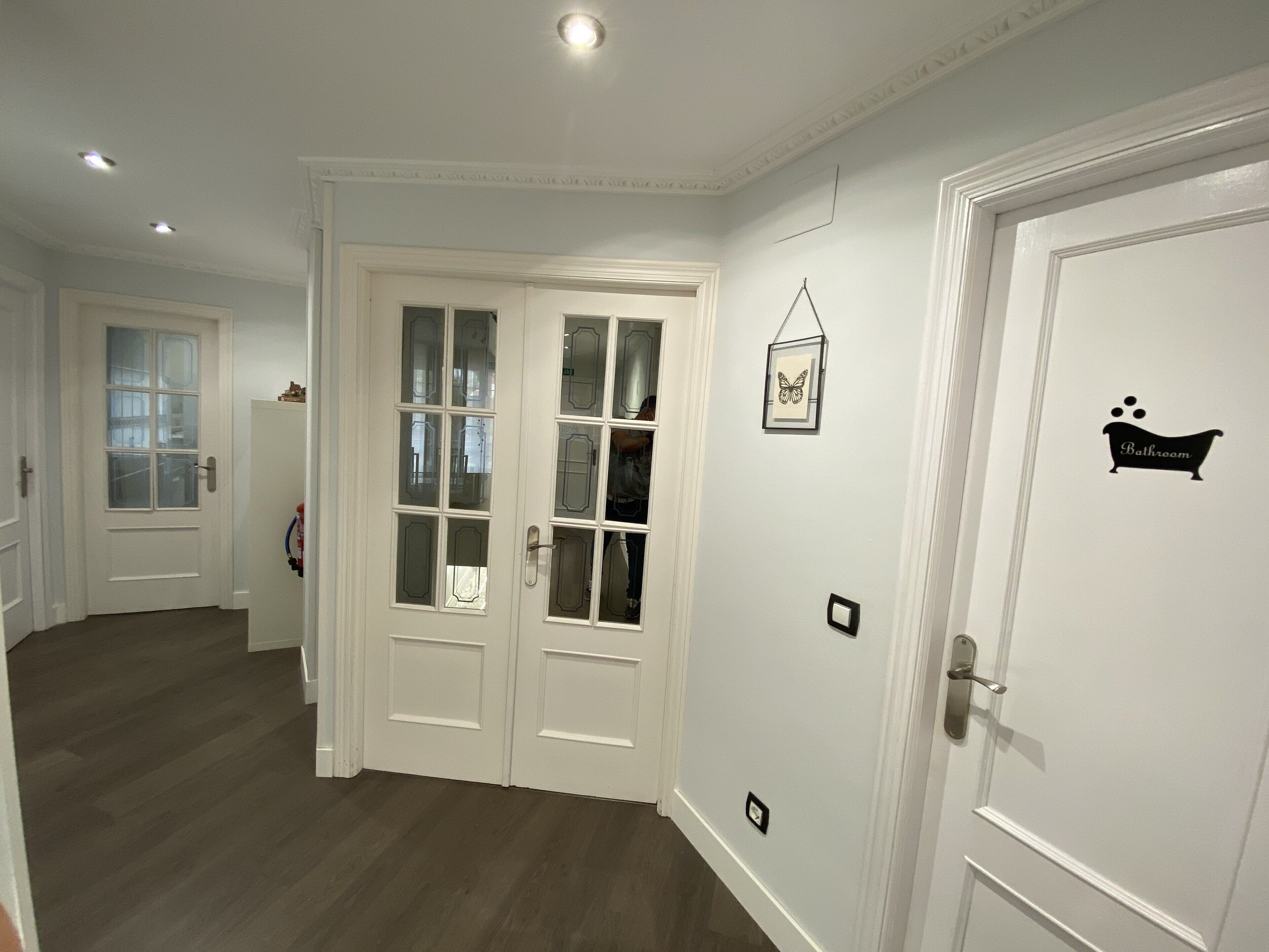 A hallway with white doors, one marked "Bathroom," and a butterfly decoration on the wall.