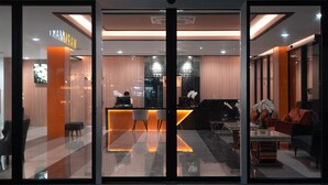A hotel reception area with a modern design, featuring a reception desk, seating area, and a visible TV screen. - KK - Karon Kata Boutique Hotel (Karon)