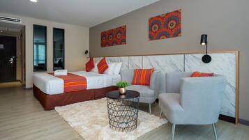 A modern hotel room with a bed, a sofa, a marble headboard, and two wall art pieces.