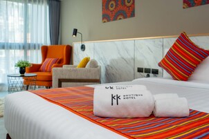 A hotel room with a bed, a chair, a small table, and a wall with a painting.